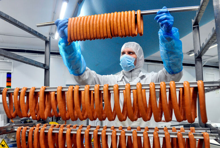 Worker in protective gear producing sausage at the Okraina meat processing plant in Murmansk. (Lev FedoseyevTASS via Getty Images)