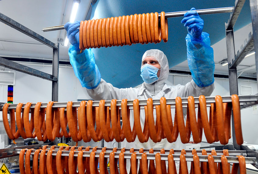 Worker in protective gear producing sausage at the Okraina meat processing plant in Murmansk. (Lev FedoseyevTASS via Getty Images)