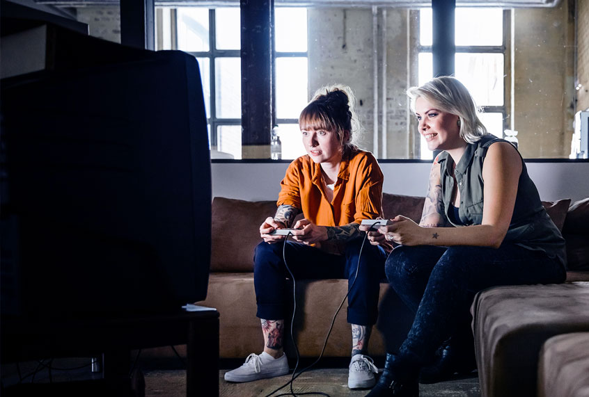 Two women playing a video game on a tv screen (Getty Images/Hinterhaus Productions)