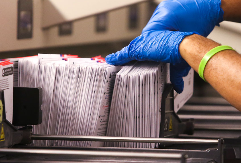 An election worker handles vote-by-mail ballots coming out of a sorting machine (JASON REDMOND/AFP via Getty Images)