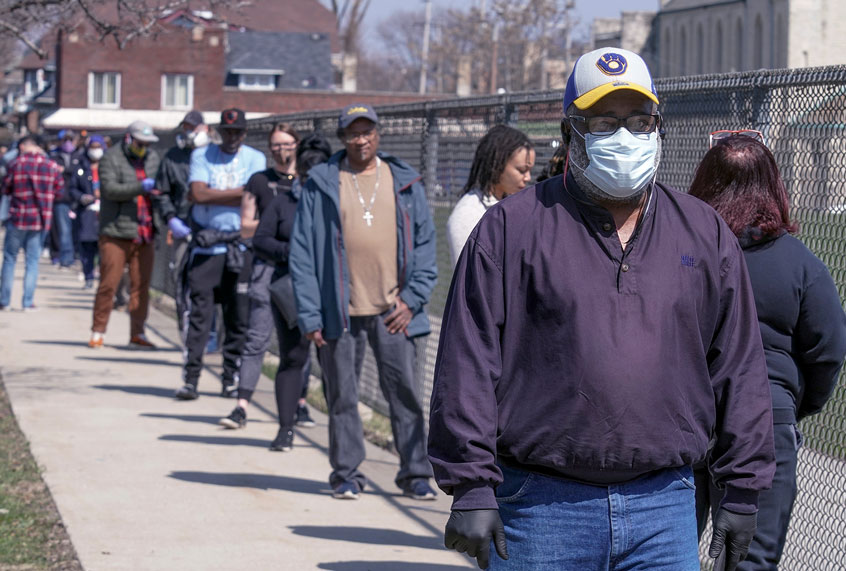 In this April 7, 2020 photo, voters observe social distancing guidelines as they wait in line to cast ballots in the presidential primary election in Milwaukee. (AP Photo/Morry Gash)