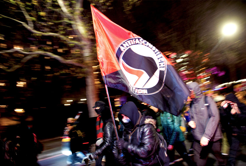 A Man charges with an Anti-Fascist flag (Getty Images)