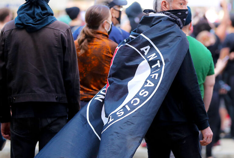 Protester with an ANTIFA flag draped over his shoulders during a rally (Matthew J. Lee/The Boston Globe via Getty Images)