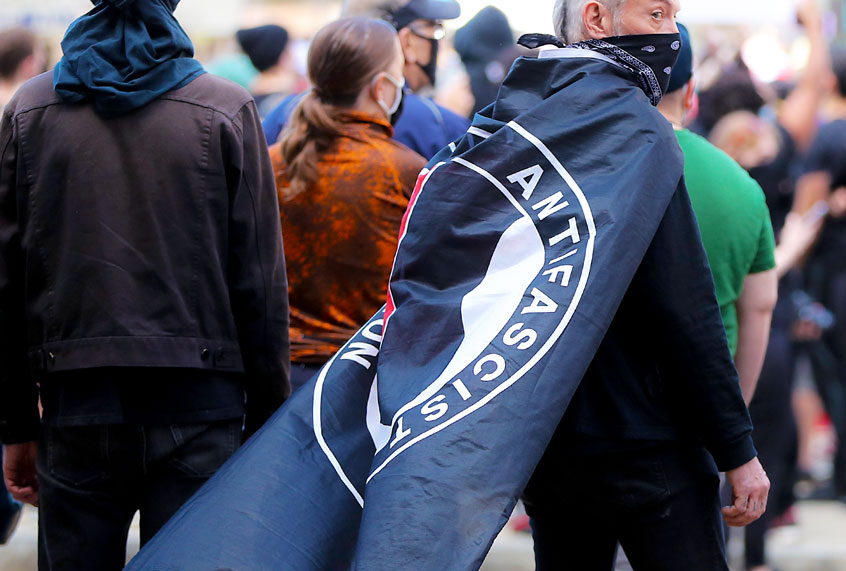 Protester with an ANTIFA flag draped over his shoulders during a rally (Matthew J. Lee/The Boston Globe via Getty Images)