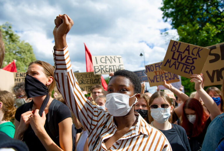 A demonstrator wearing a protective face mask holds her fist high during a protest (Aleksander Kalka/NurPhoto via Getty Images)