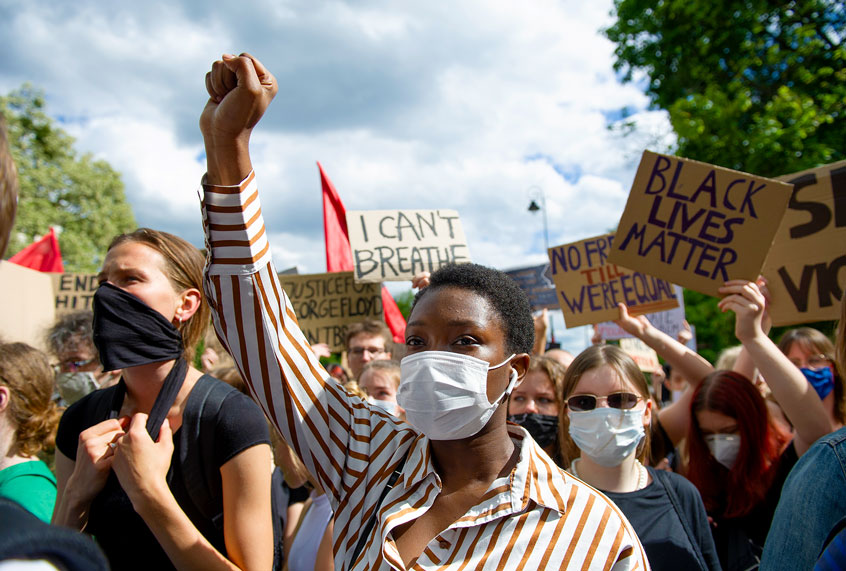 A demonstrator wearing a protective face mask holds her fist high during a protest (Aleksander Kalka/NurPhoto via Getty Images)