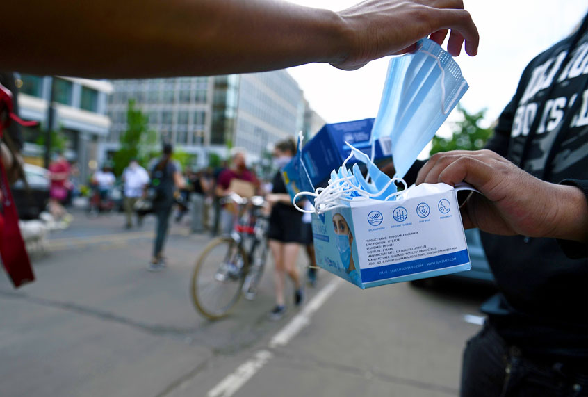 A person gives aways face-masks to people during a demonstration over the death of George Floyd, who died in police custody in Minneapolis, near the White House, in Washington, DC (BRENDAN SMIALOWSKI/AFP via Getty Images)