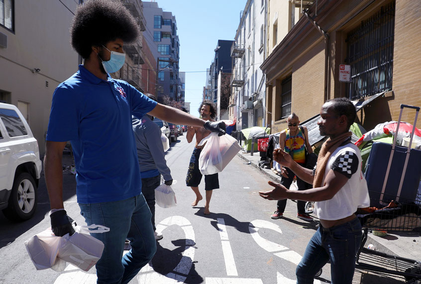 After school program and day camp lead Francisco Craig (left) hands out care packages on Willow near Polk St. in the Tenderloin on Tuesday, April 28, 2020, in San Francisco, Calif. (Liz Hafalia/The San Francisco Chronicle via Getty Images)