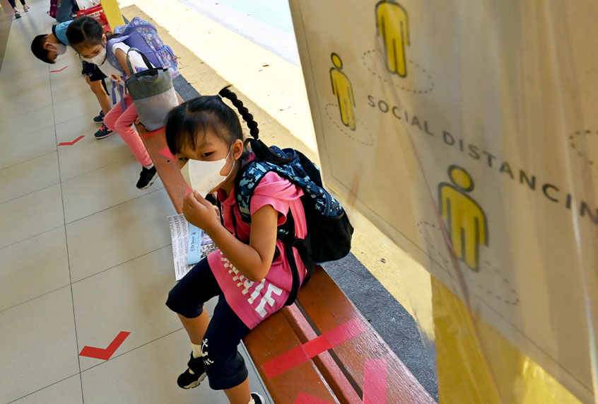 Students sitting on a bench with markers for social distancing to prevent the spread of the COVID-19 novel coronavirus (ROMEO GACAD/AFP via Getty Images)