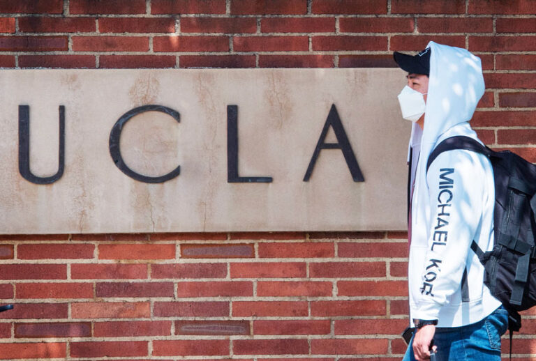 A student wears a face mask to protect against the COVID-19 (Coronavirus) as he leaves the campus of the UCLA college in Westwood, California (MARK RALSTON/AFP via Getty Images)