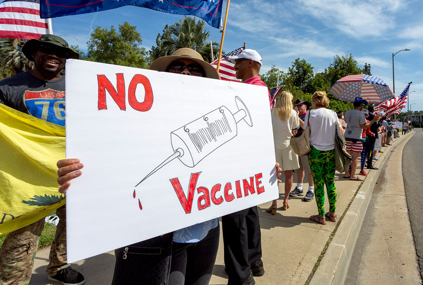A protester holds an anti-vaccination sign as supporters of President Donald Trump rally to reopen California as the coronavirus pandemic continues to worsen, on May 16, 2020 in Woodland Hills, California. (David McNew/Getty Images)