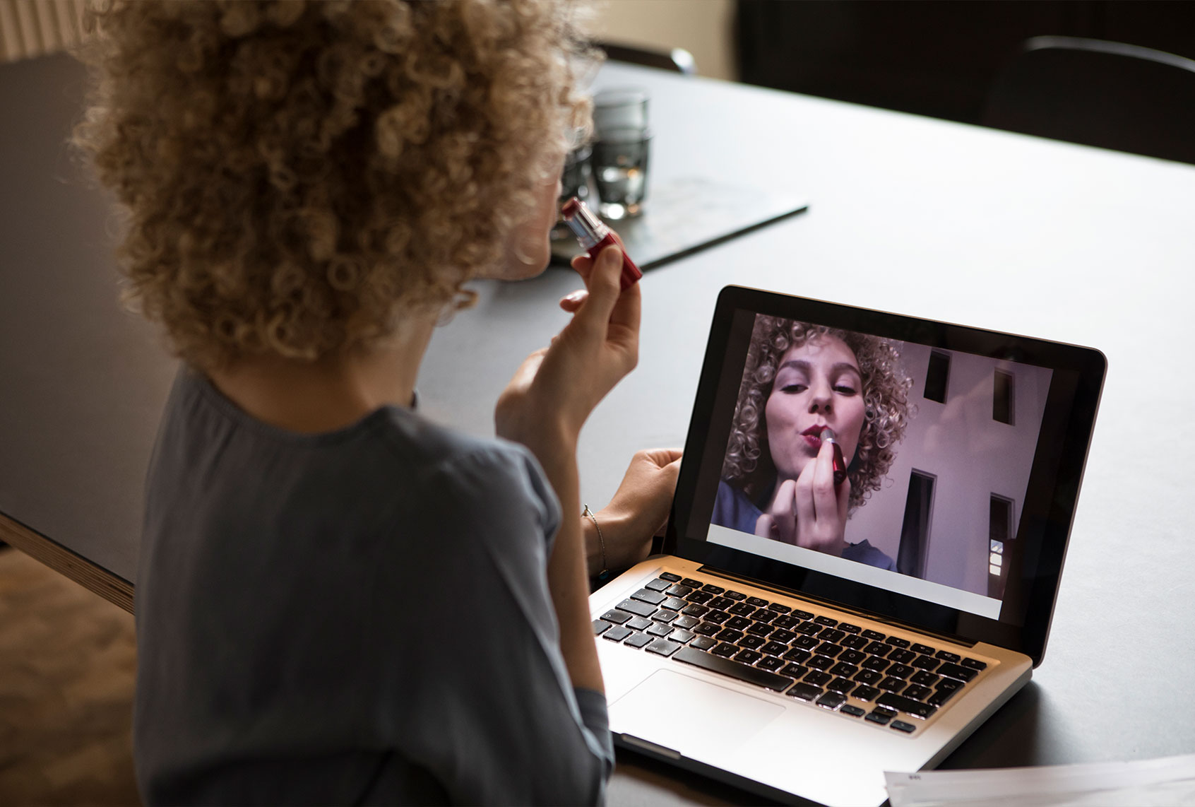 Woman in office applying make-up using laptop monitor as mirror (Getty Images)
