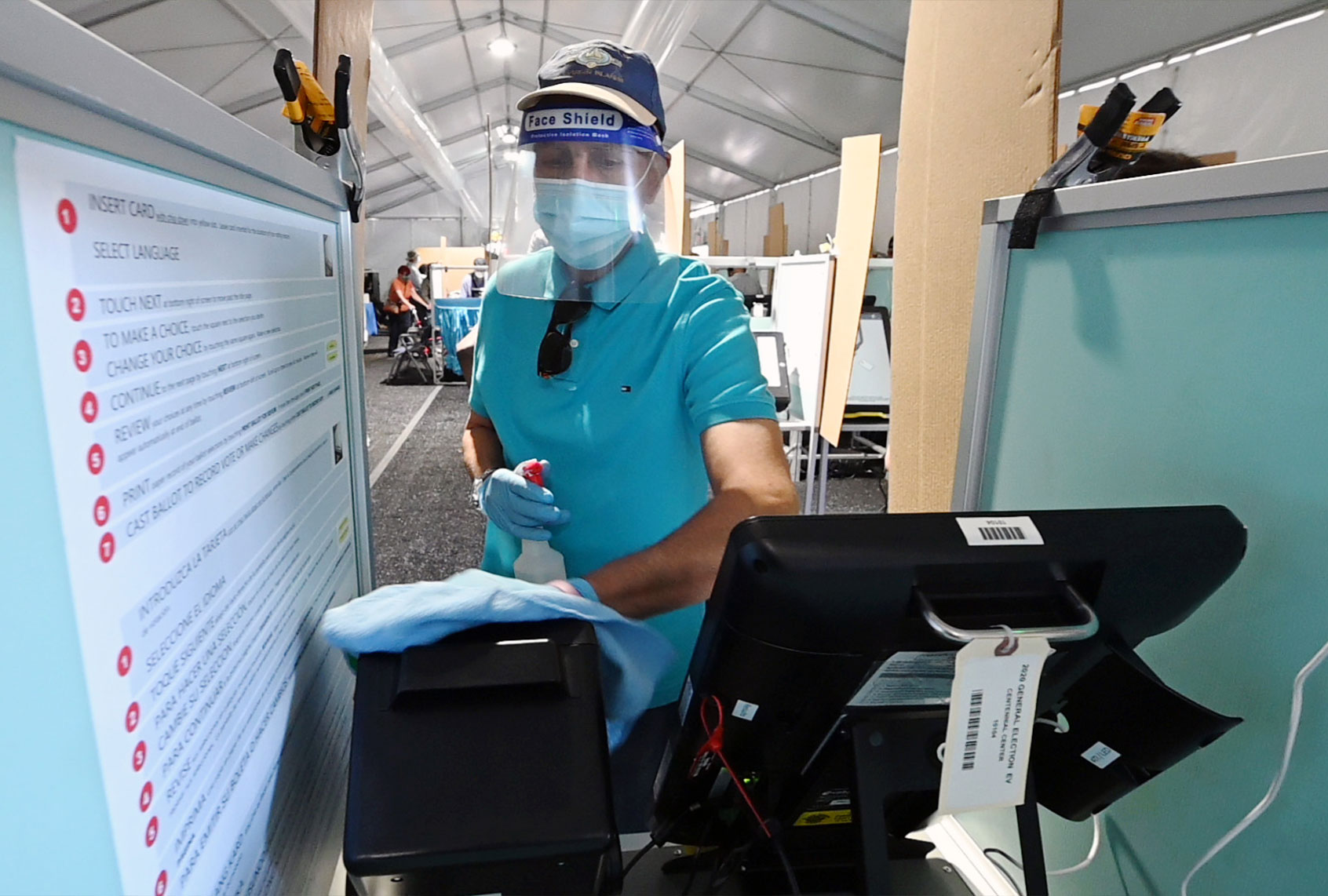 Carl Chamberlain sanitizes a voting booth between voters inside a tent at a shopping center on the first day of in-person early voting on October 17, 2020 in Las Vegas, Nevada. Early voting for the general election in the battleground state continues through October 30. (Ethan Miller/Getty Images)