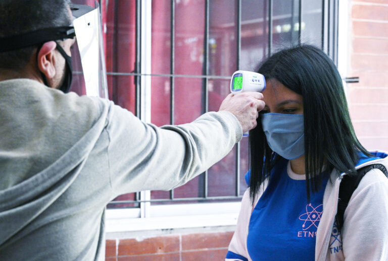 Workers at a high school check the temperature to a student before she enters to attend classes in Buenos Aires, Argentina, on October 13, 2020 amid the virus lockdown against the spread of the novel coronavirus, COVID-19 pandemic. (JUAN MABROMATA/AFP via Getty Images)