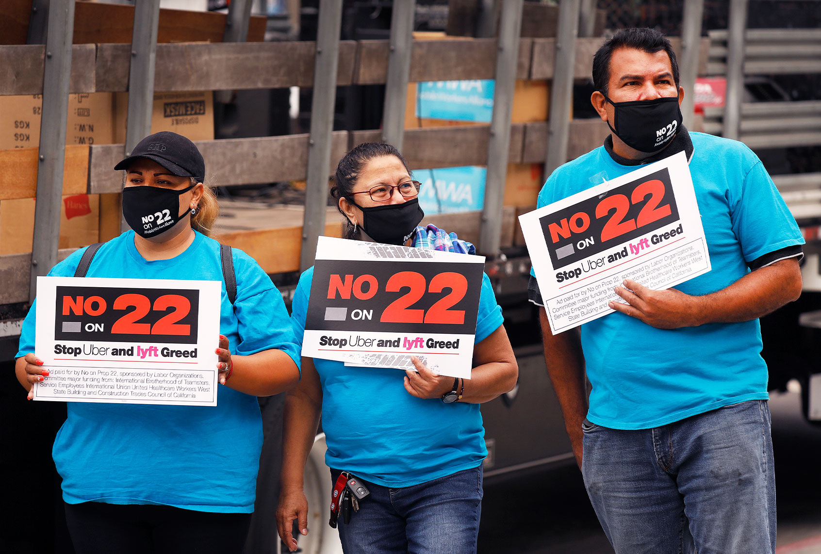 Luz Laguna, Isabelle Ramos and Leonardo Diaz, left to right, with Mobile Workers Alliance hold signs in support as app based gig workers held a driving demonstration with 60-70 vehicles blocking Spring Street in front of Los Angeles City Hall urging voters to vote no on Proposition 22, a November ballot measure that would classify app-based drivers as independent contractors and not employees or agents, providing them with an exemption from Californias AB 5. (Al Seib / Los Angeles Times)