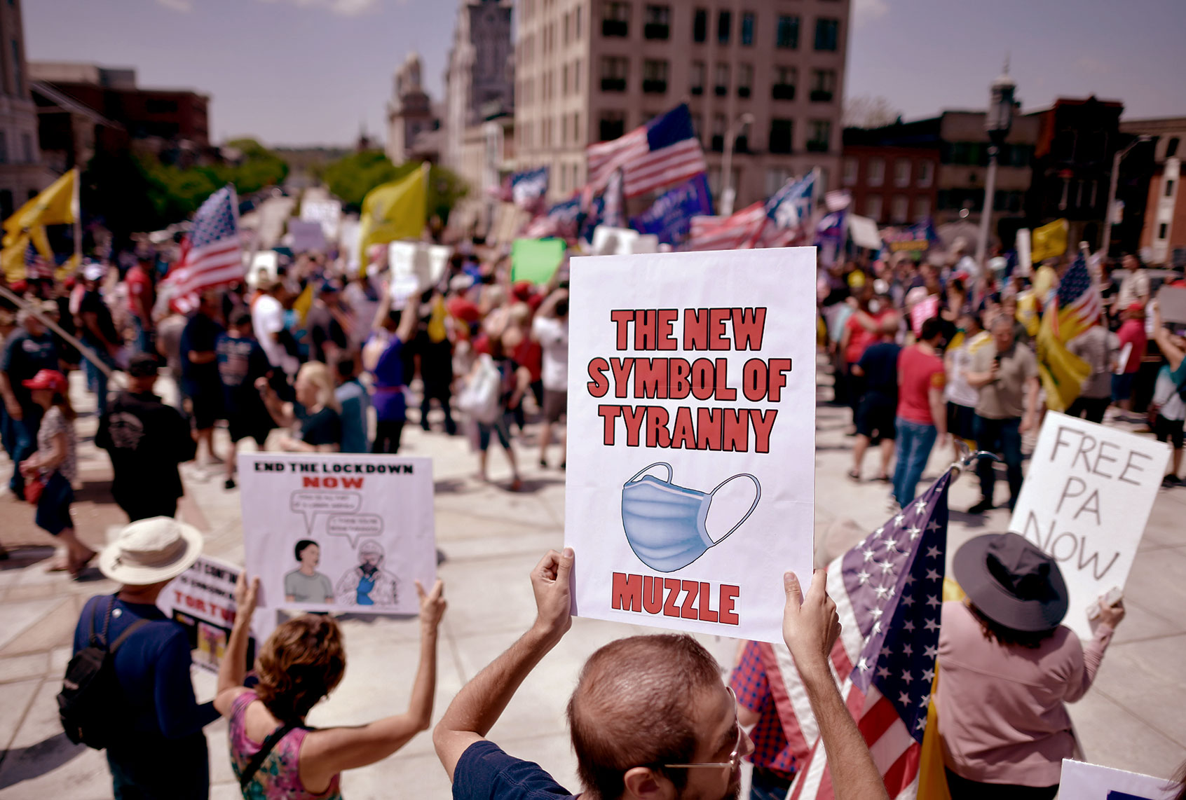 A demonstrator holds a placard with a face mask stating "THE NEW SYMBOL OF TYRANNY MUZZLE" rallying outside the Pennsylvania Capitol Building to protest the continued closure of businesses due to the coronavirus pandemic on May 15, 2020 in Harrisburg, Pennsylvania. (Mark Makela/Getty Images)