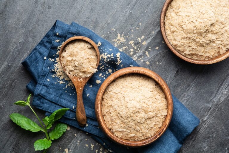 Dietary supplement, unfortified nutritional yeast flakes in a wooden bowl and scoop. (Getty Images)