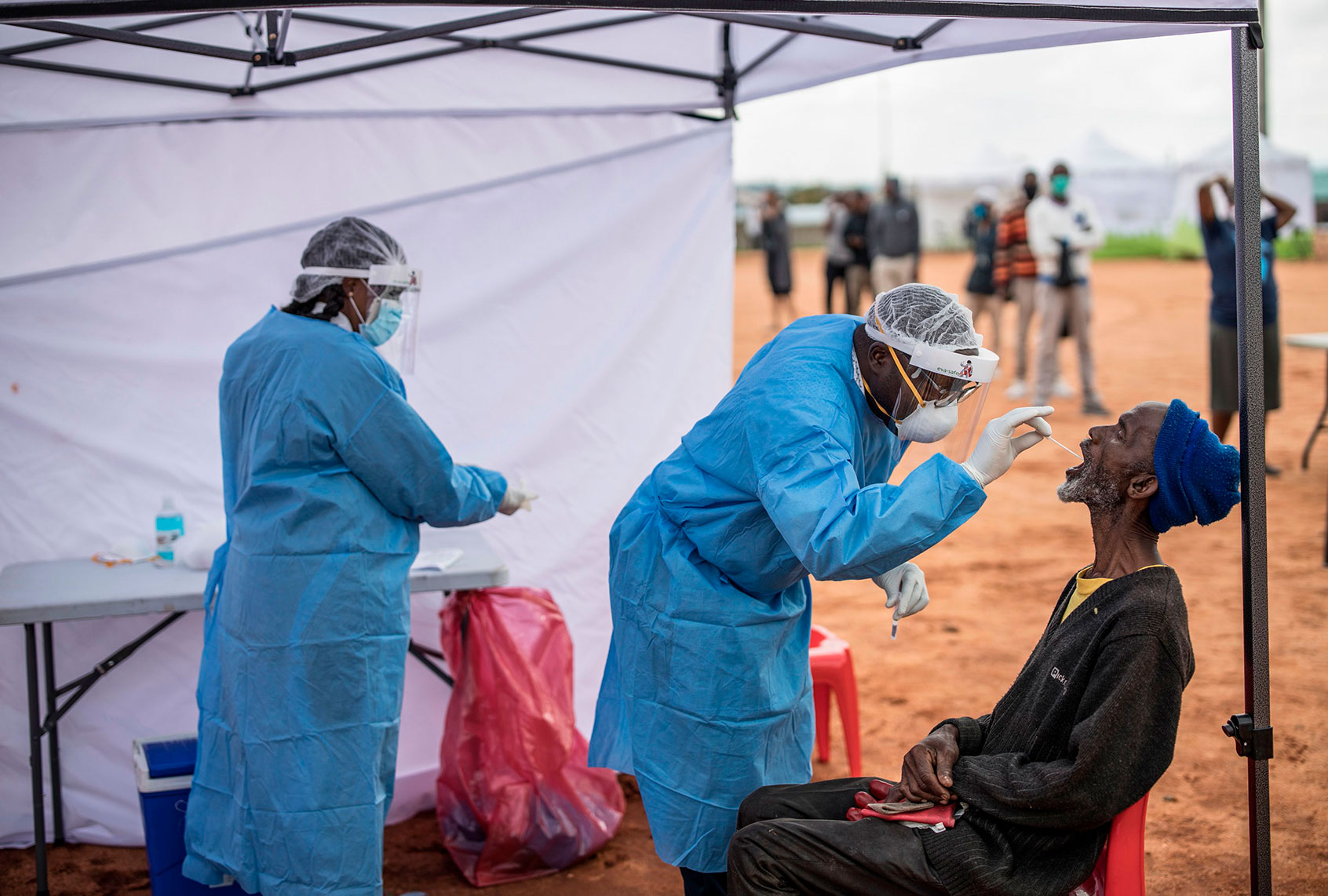 An elderly man, a resident of the sprawling township of Alexandra in Johannesburg, opens his mouth to receive a testing swab for COVID-19 coronavirus at a screening and testing drive in front of the Madala Hostel, on April 27, 2020. (Photo by MARCO LONGARI / AFP) (MARCO LONGARI/AFP via Getty Images)