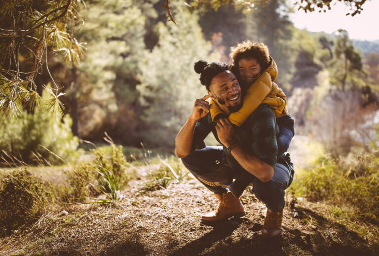 Dad and son bonding and having fun with piggyback ride on mountain hiking adventure (Getty Images)