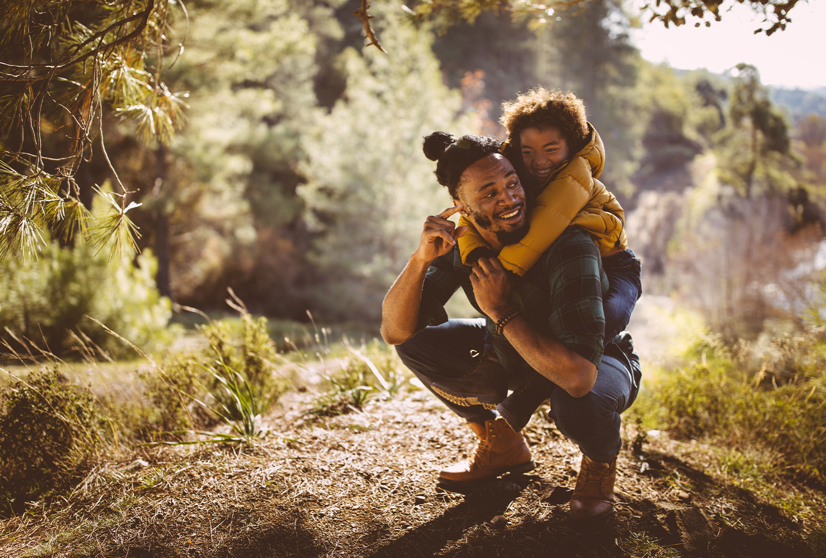 Dad and son bonding and having fun with piggyback ride on mountain hiking adventure (Getty Images)