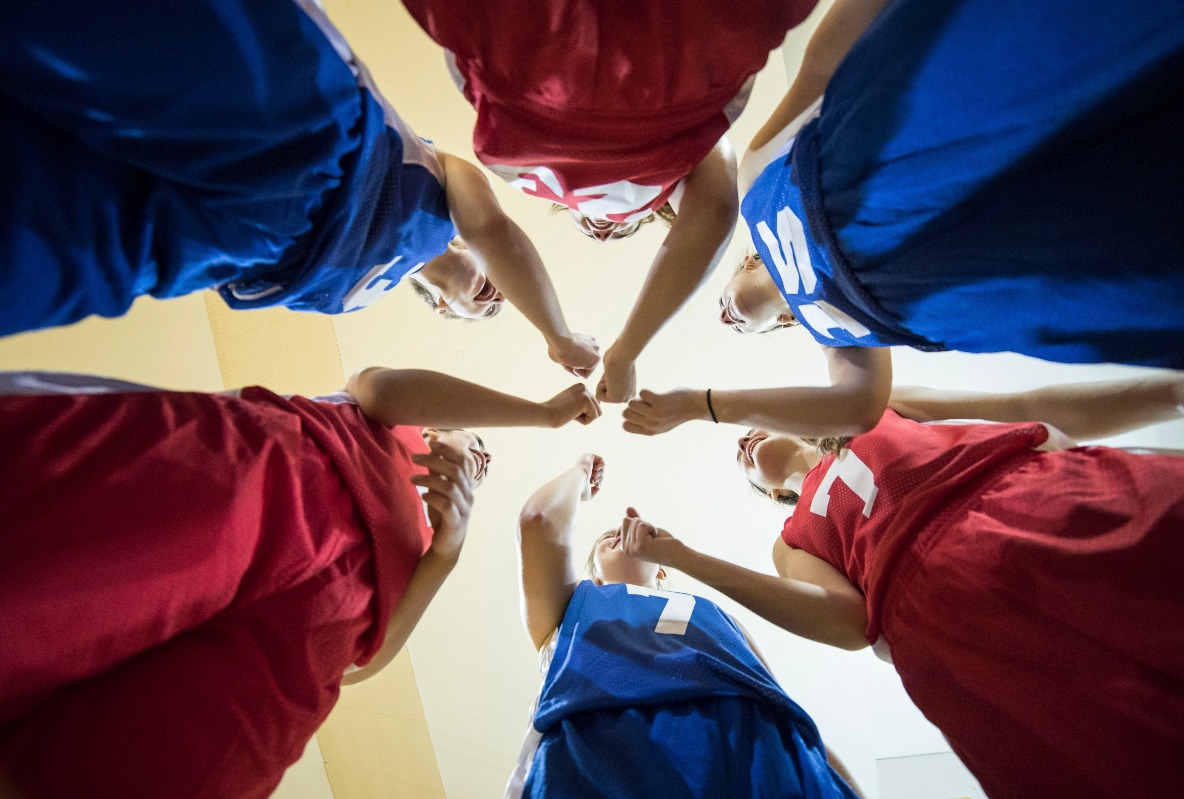 Diverse teenage girl athletes cheering after their team huddle (Getty)
