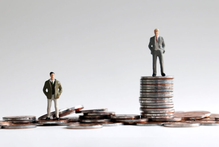 Miniature people standing on a pile of coins (Getty Images)