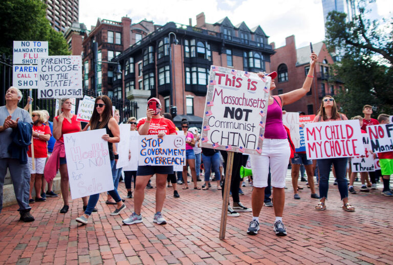 Anti-vaccine activists protest and hold signs in front of the Massachusetts State House against Governor Charlie Baker's mandate that all Massachusetts school students enrolled in child care, pre-school, K-12, and post-secondary institutions must receive the flu vaccine this year on August 30, 2020 in Boston, Massachusetts. (Scott Eisen/Getty Images)