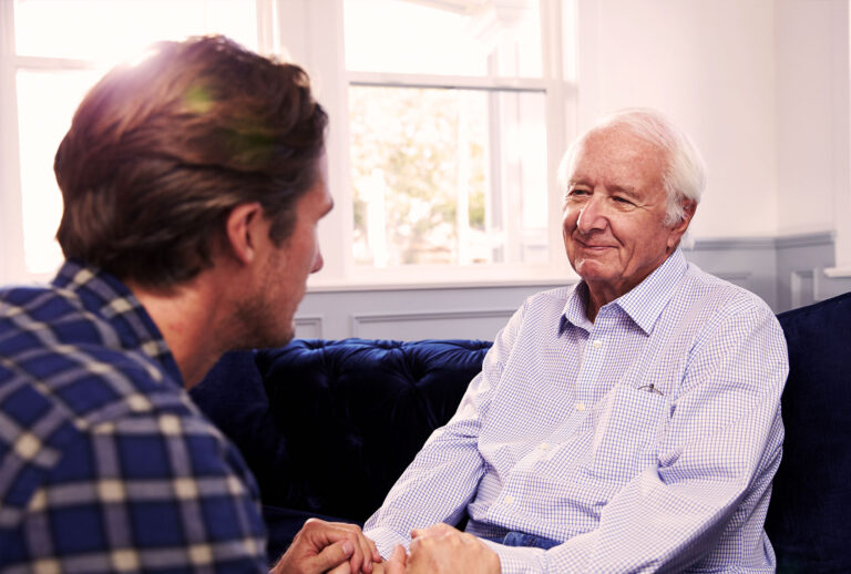 Adult Son Talking To Father At Home (Getty Images)