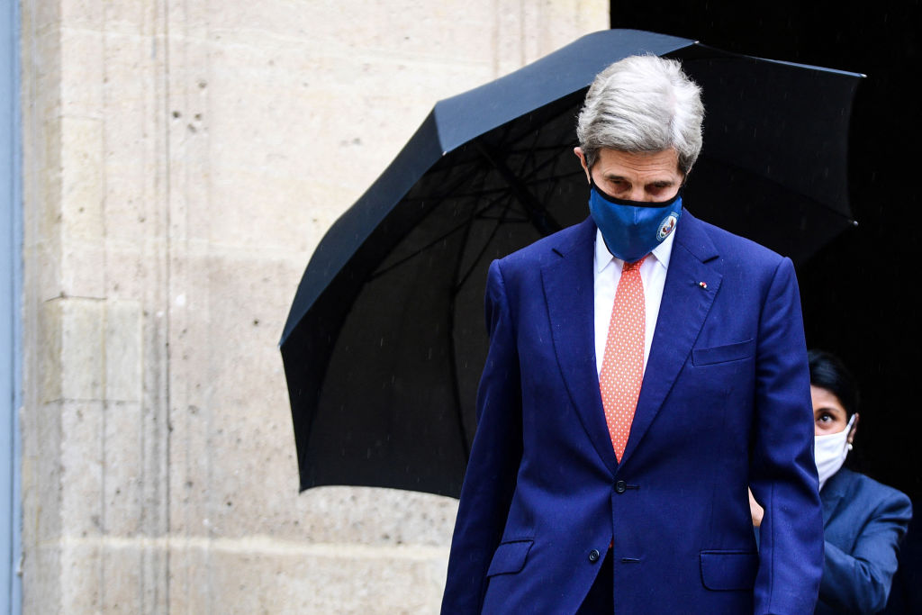 A member of staff holds the umbrella for US climate envoy John Kerry as he leaves the Hotel Roquelaure following his meeting French Ecological Transition Minister, in Paris, on March 11, 2021. (Photo by MARTIN BUREAU/AFP via Getty Images)