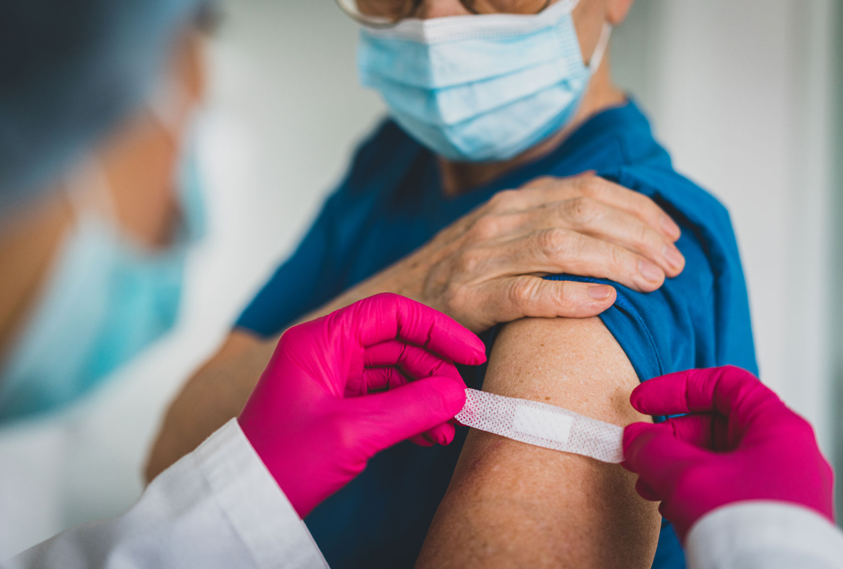 Doctor giving first aid bandage after vaccination to senior woman (Jasmin Merdan/Getty Images)