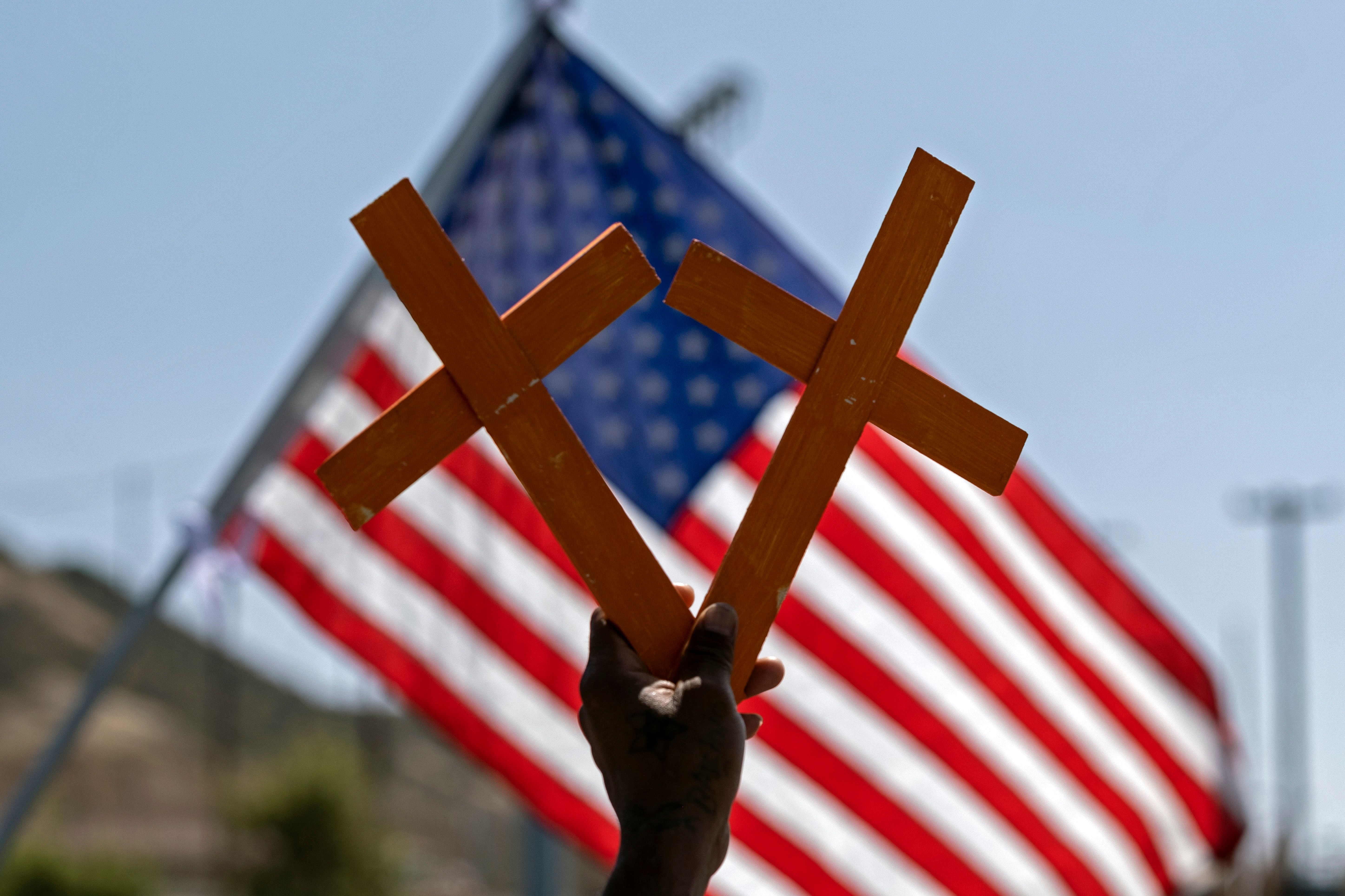 Crosses in front of a US flag. (GUILLERMO ARIAS/AFP via Getty Images)