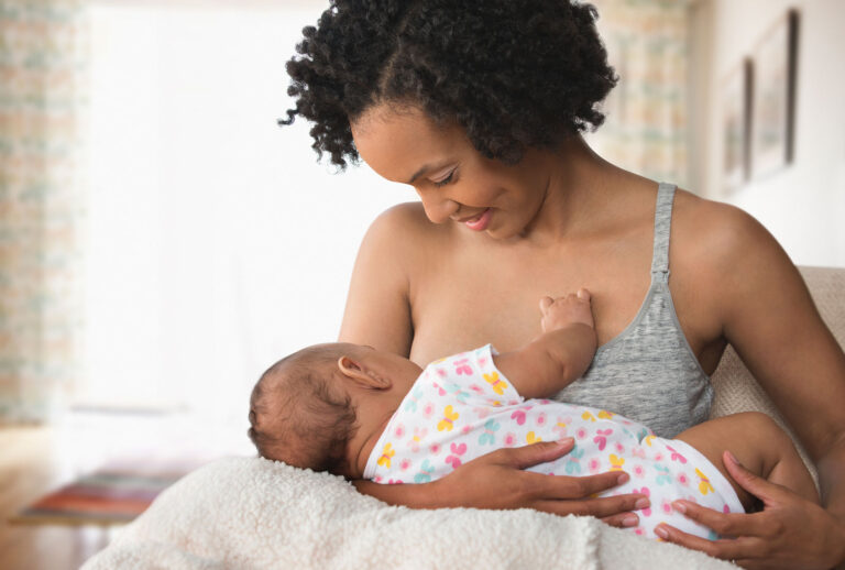 Mother breastfeeding baby in living room (Getty Images)