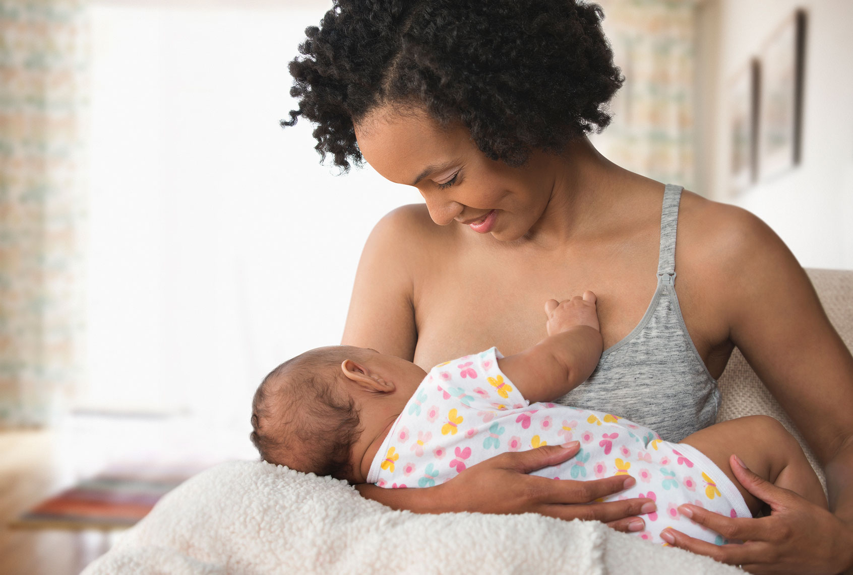 Mother breastfeeding baby in living room (Getty Images)
