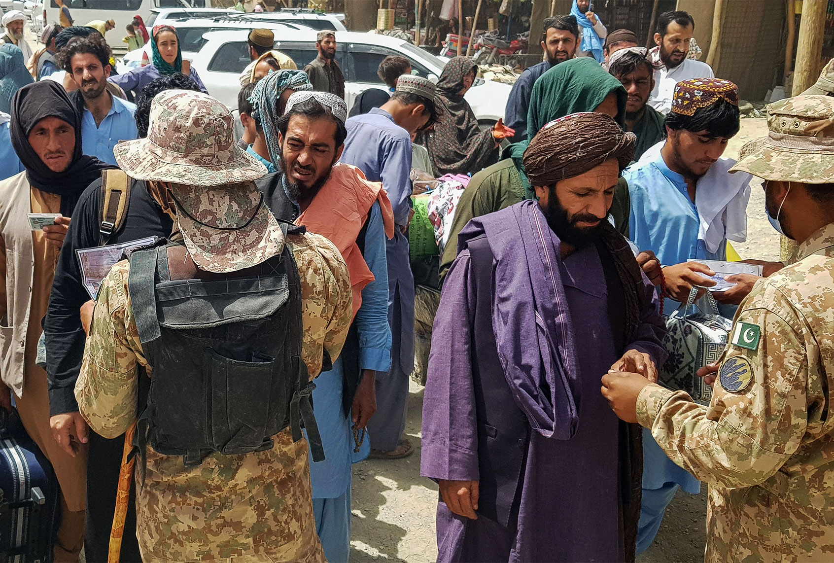 Pakistani soldiers check the documents of stranded Afghan nationals wanting to return to Afghanistan at the Pakistan-Afghanistan border crossing point in Chaman on August 15, 2021, after the Taliban took control of the Afghan border town in a rapid offensive across the country. (AFP via Getty Images)