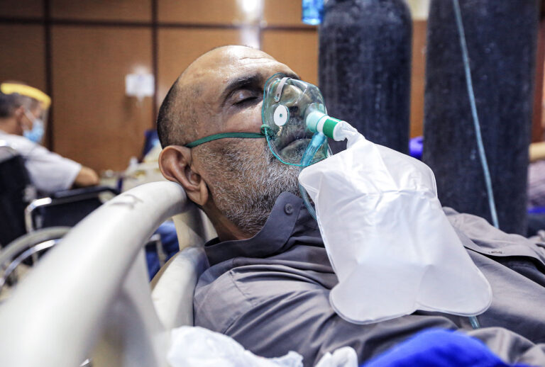 A coronavirus patient lies on a bed inside in a ward at Al-Ataa hospital. (Ameer Al Mohammedaw/picture alliance via Getty Images)