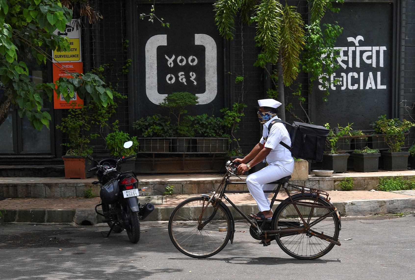 "Dabbawala", Mumbai's famed cycle-borne tiffin delivery men, Pandurang Jadhav cycles to make a food delivery in Mumbai. - After the pandemic shut offices and put Mumbai's renowned lunchbox deliverymen out of work, the 130-year-old "Dabbawala" network has tied up with a trendy restaurant chain to take on India's billion-dollar start-ups. (INDRANIL MUKHERJEE/AFP via Getty Images)