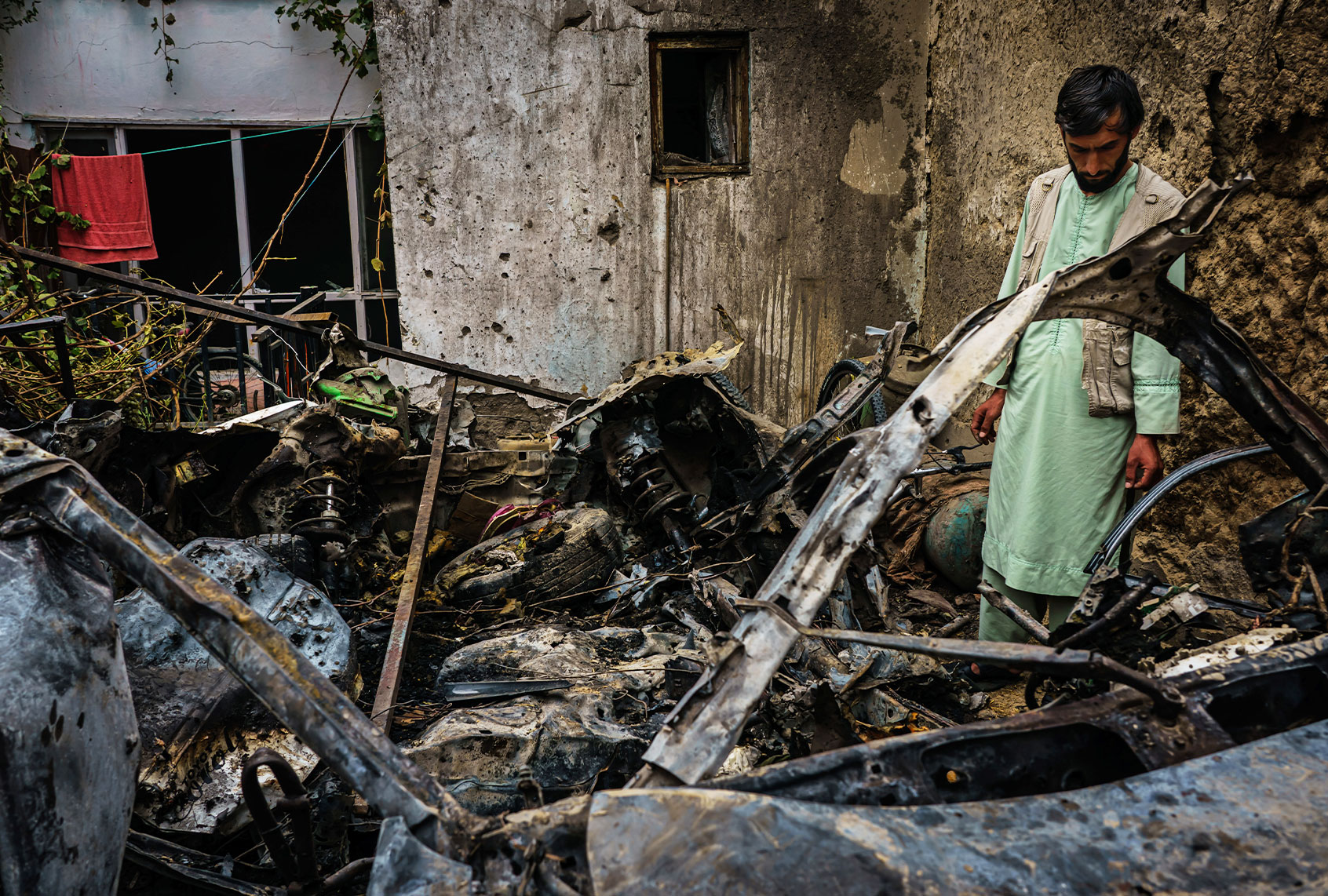 Relatives and neighbors of the Ahmadi family gathered around the incinerated husk of a vehicle targeted and hit earlier Sunday afternoon by an American drone strike, in Kabul, Afghanistan, Monday, Aug. 30, 2021. (Marcus Yam/Los Angeles Times/Getty Images)
