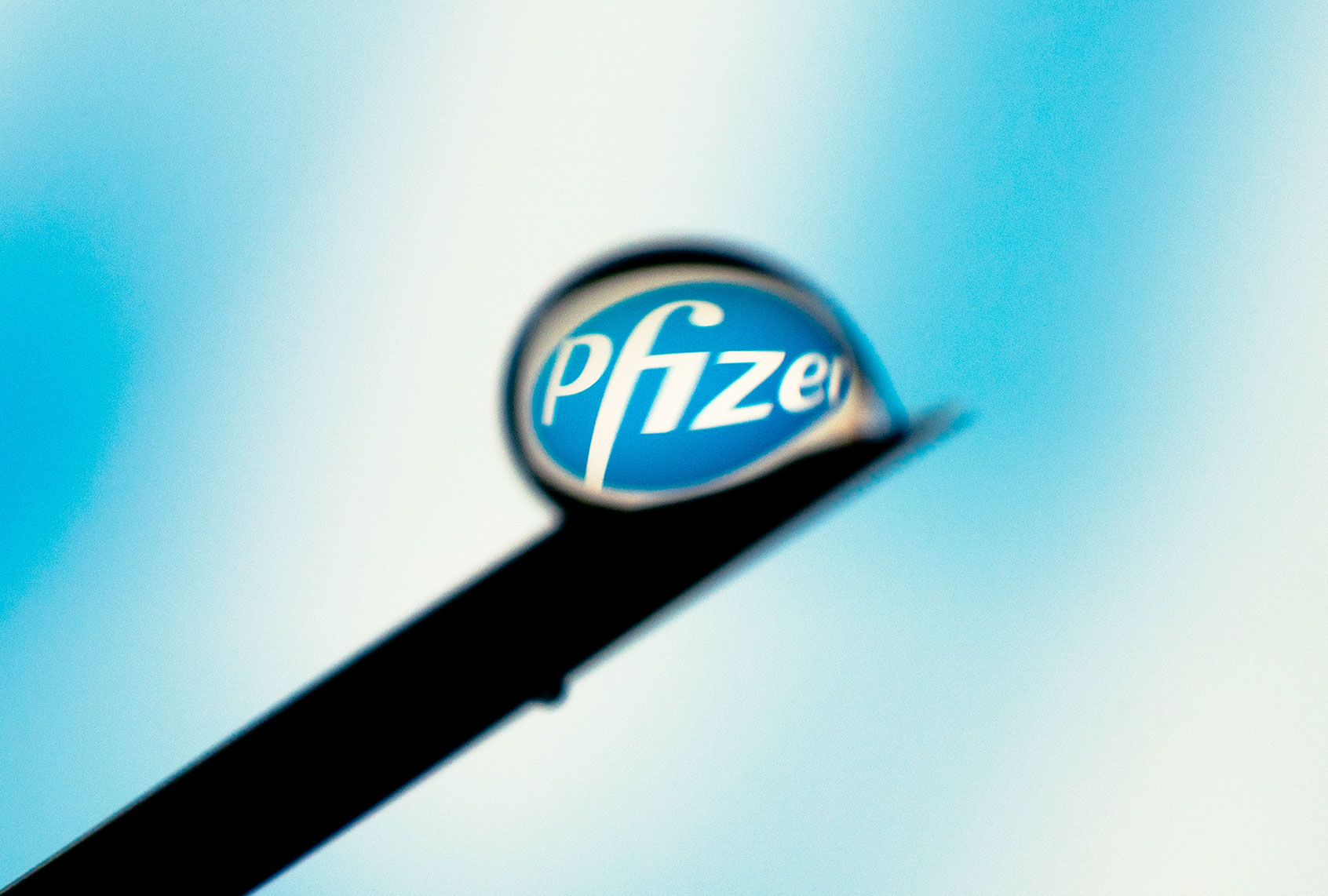 The Pfizer logo is seen reflected in a drop on a needle (Jaap Arriens/NurPhoto via Getty Images)