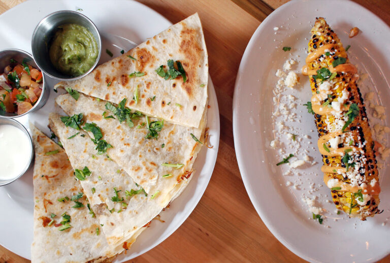 Carnitas quesadilla with guacamole, Mexican crema and pico de gallo, left, and grilled Mexican-style corn on the cob with chipotle aioli, cotija cheese and cilantro at El Corazon, 190 State St., Portland. (Ben McCanna/Portland Portland Press Herald via Getty Images)