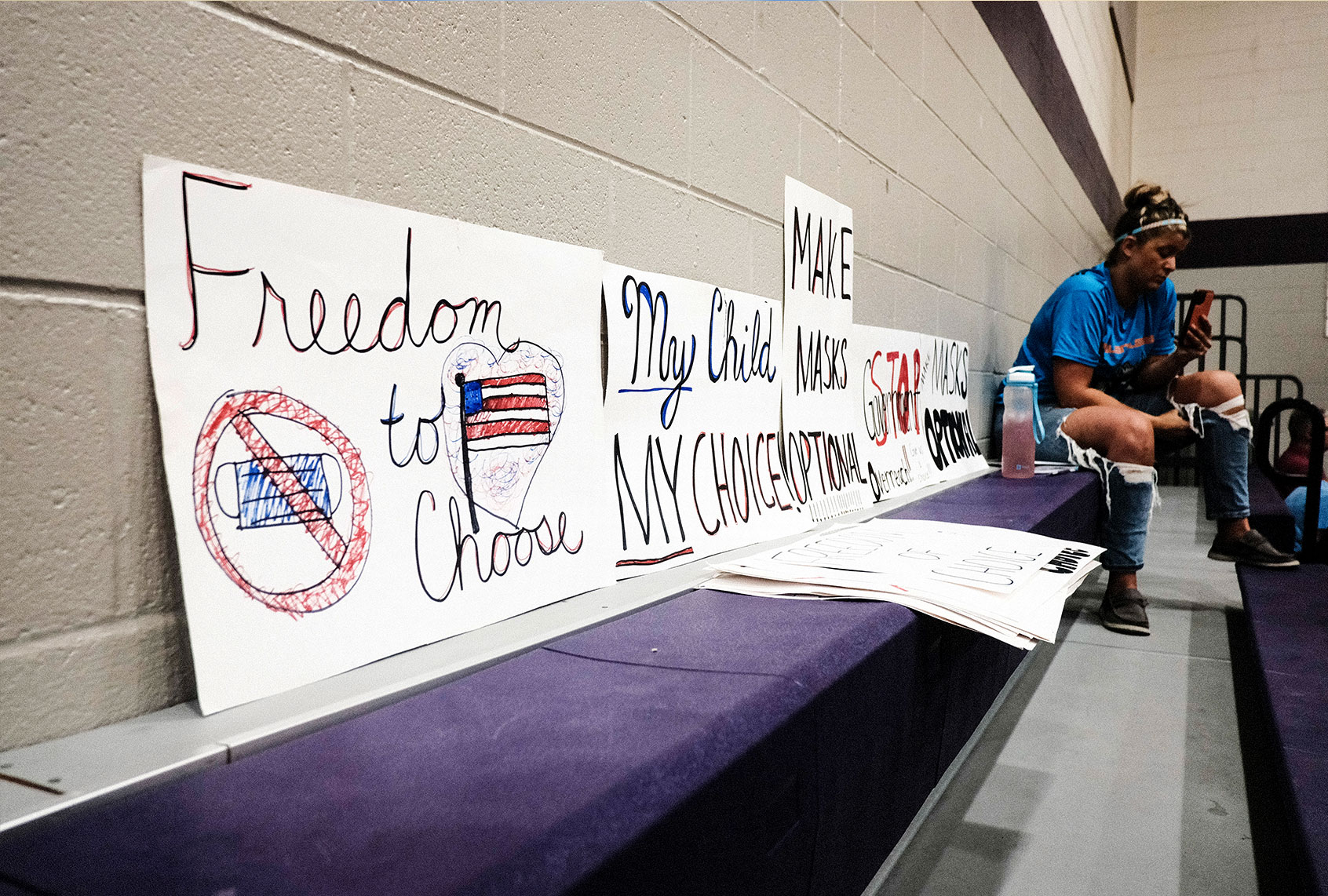 An attendee sits next to anti-vaccine mandate signs at a special Board of Education Meeting on mask mandates for students and staff in Kalamazoo County Schools at the Schoolcraft High School Gymnasium on August 23, 2021 in Schoolcraft, Michigan. The Schoolcraft Local School District opened the floor for public discussion. (Matthew Hatcher/Getty Images)