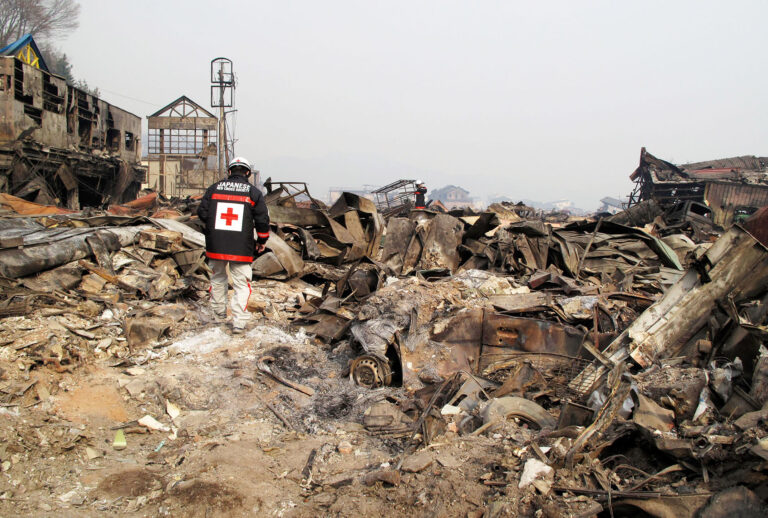 In this handout images provided by the International Federation of Red Cross Japan, A member of the Japanese Red Cross team walks through what is left of the city of Otsuchi, after an 9.0 magnitude strong earthquake struck on March 11, off the coast of north-eastern Japan, March 14, 2011 in Otsuchi, Japan. The quake struck offshore at 2:46pm local time, triggering a tsunami wave of up to 10 metres which engulfed large parts of north-eastern Japan. On Tuesday there was a third explosion from the Fukushima Daiichi nuclear power plant causing fears for the radiation levels being emitted from the plant. (Patrick Fuller/Japanese Red Cross/IFRC via Getty Images)