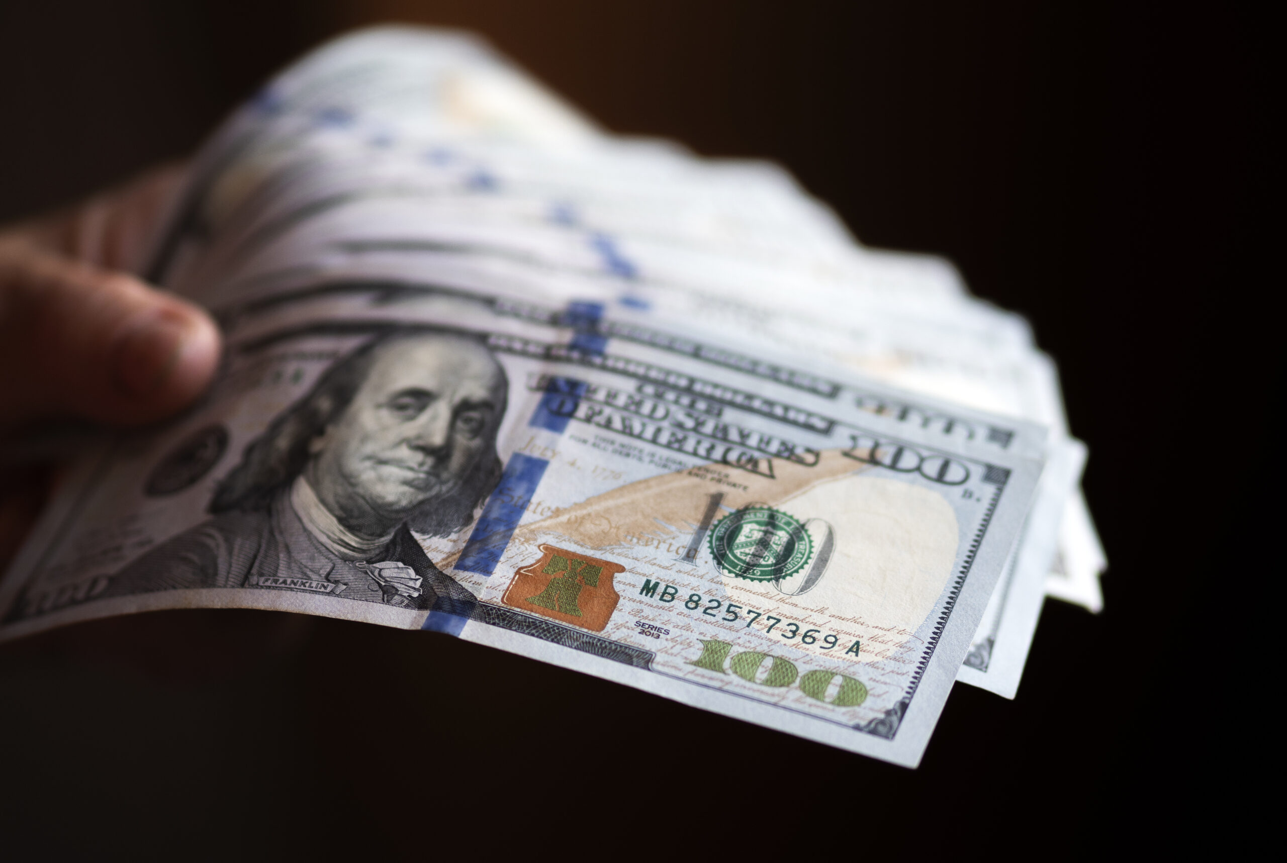 A hand holding several $100 bills. (Getty Images)