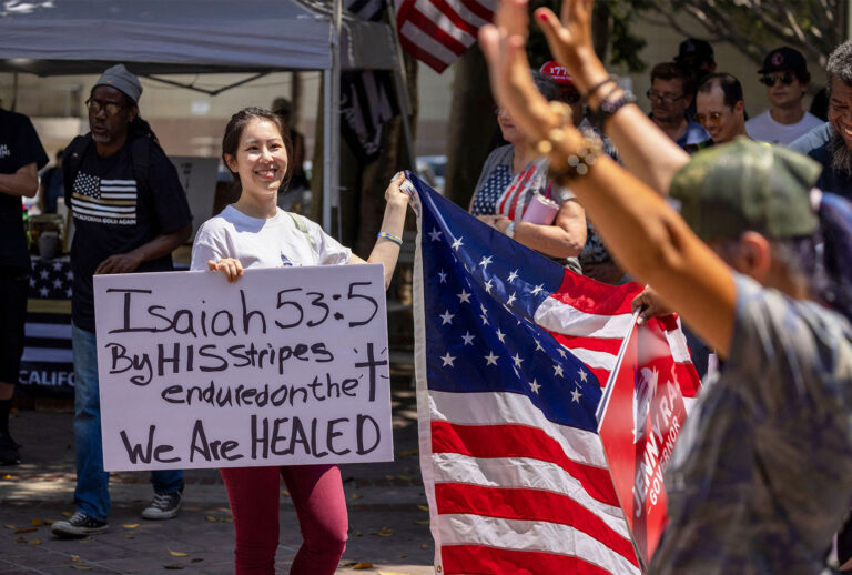 A woman holds a sign quoting the Bible as anti-vaccination protesters pray and gather near Los Angeles City Hall on August 14, 2021 (DAVID MCNEW/AFP via Getty Images)