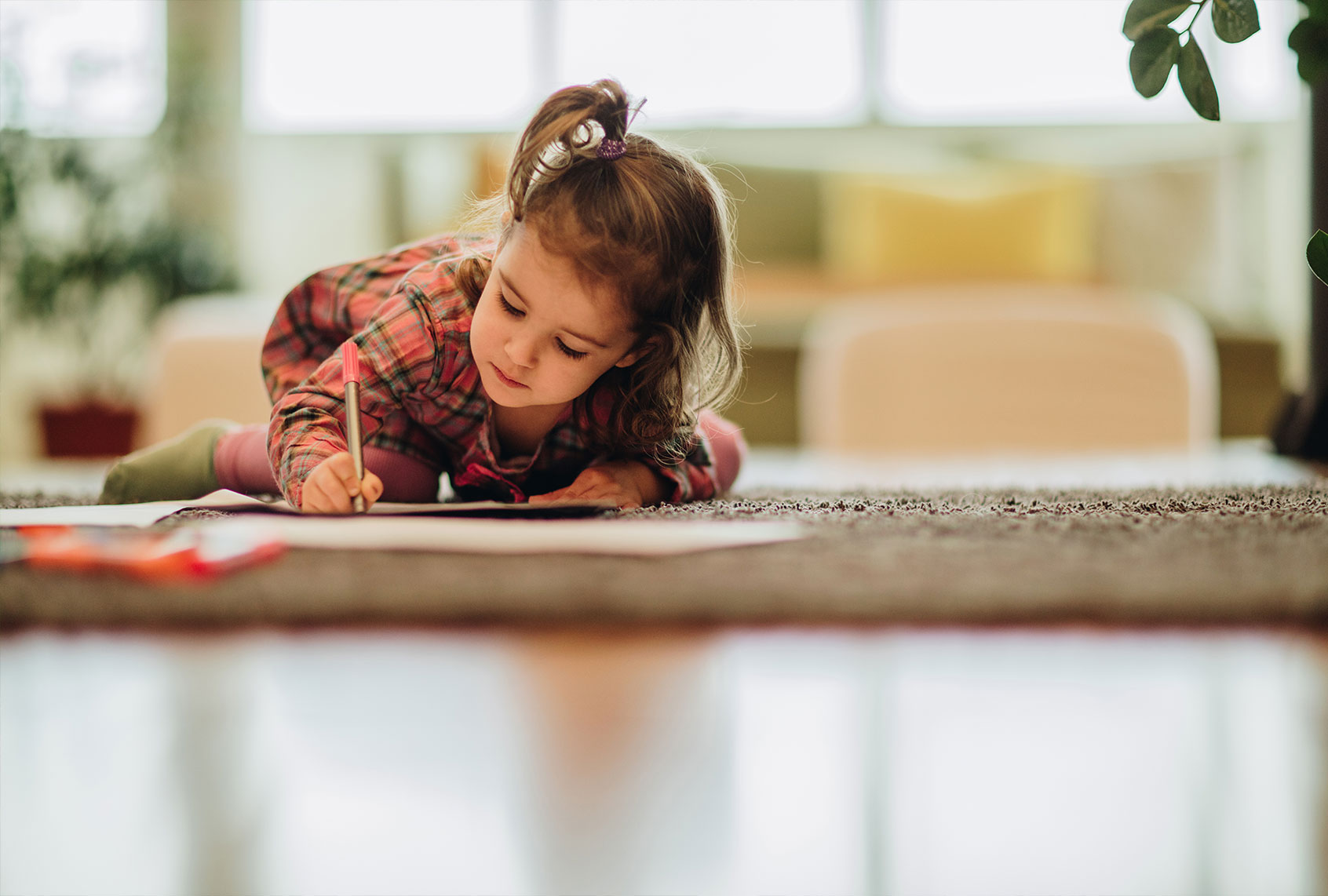 Small girl writing with felt tip pen while relaxing on the carpet at home (Getty Images/skynesher)