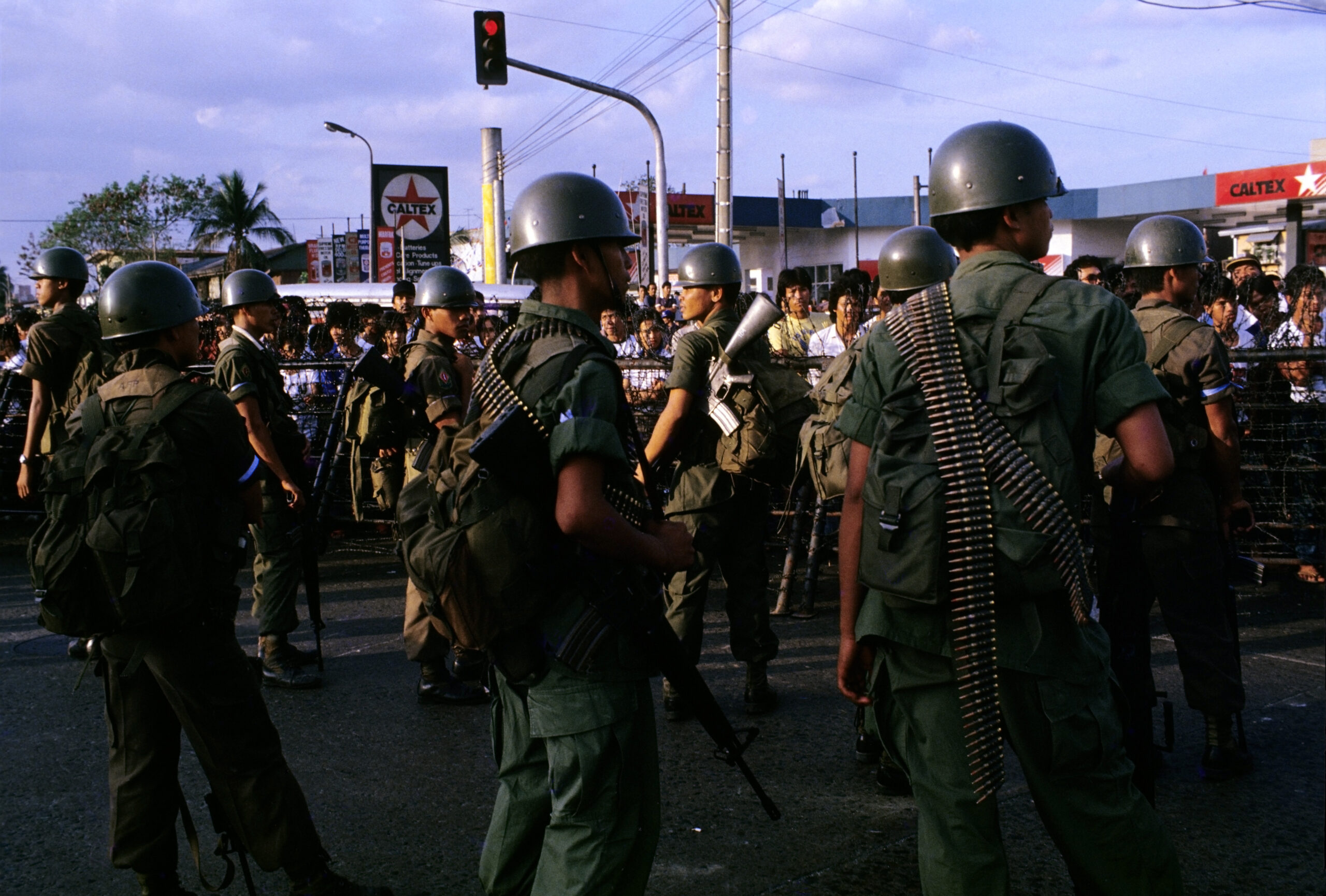 Pro-Marcos soldiers face supporters of opposition leader Cory Aquino across metal barricades strung with barbed wire outside Malacanang Palace home of President Ferdinand Marcos, Manila, Feb. 25, 1986. The mass demonstrations, which came to be known as the People Power Revolution, toppled Marcos after four days. (Alex Bowie/Getty Images)