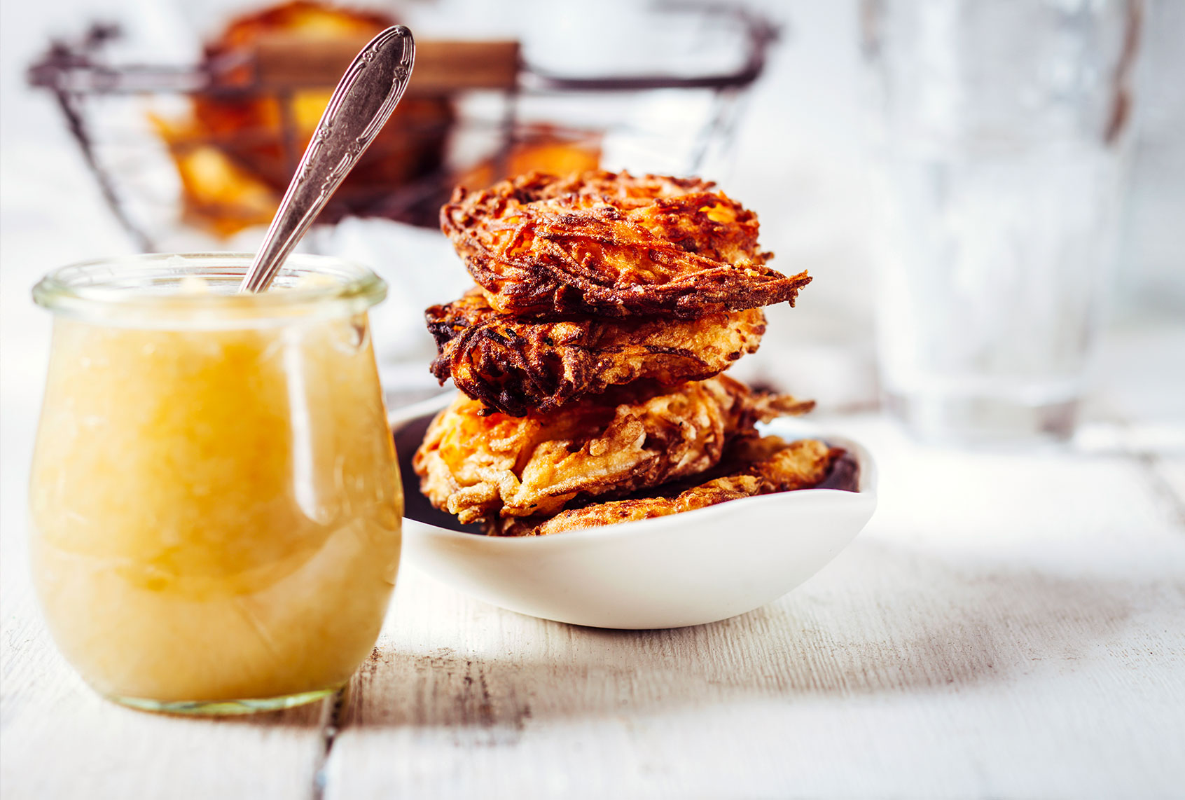 Jar of apple sauce and bowl of crispy potato latkes (Getty Images/Westend61)