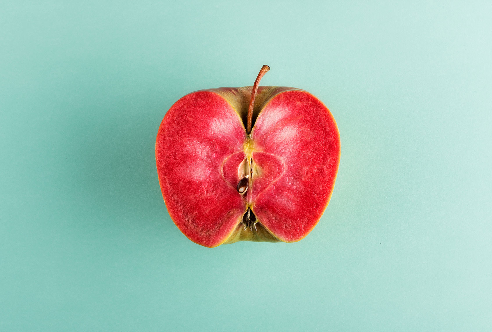 Sliced in half apple fruit with vivid red flesh (Getty Images/Photology1971)