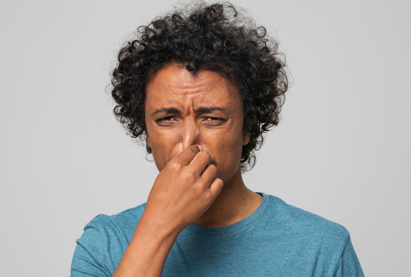 Young man holding nose (Getty Images/simonkr)