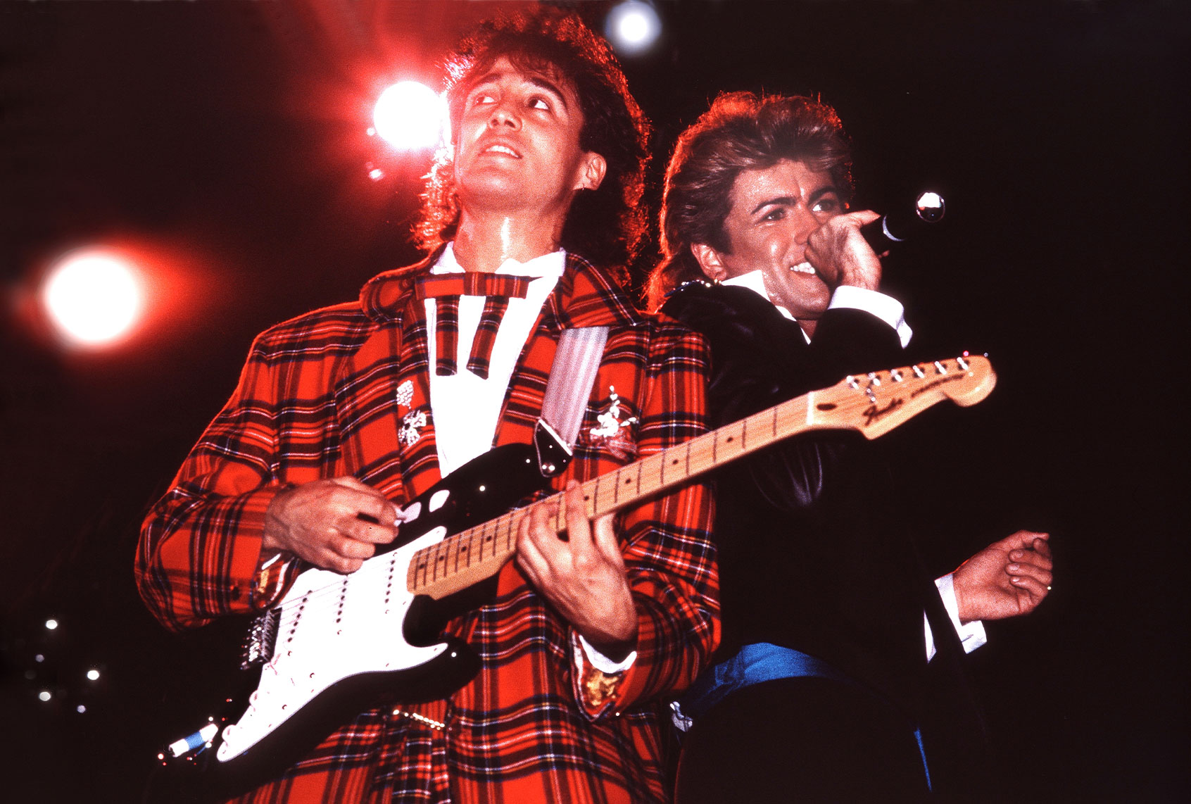 Andrew Ridgeley and George Michael of Wham! perform on stage in London, 1984. (Photo by Phil Dent/Redferns/Getty Images)