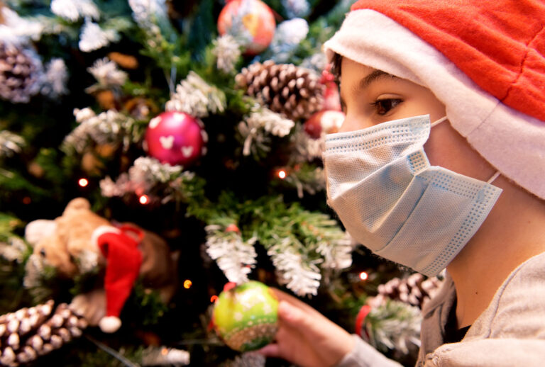 A child with a mask with a Christmas hat decorates the Christmas tree in his house (Simona Granati - Corbis/Getty Images)